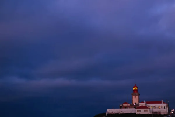 Um farol em uma colina contra o pano de fundo de escuro e tempestuoso — Fotografia de Stock