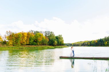 birbirlerine kucaklayan ve göle orman arka planı iskelede duran sevgili