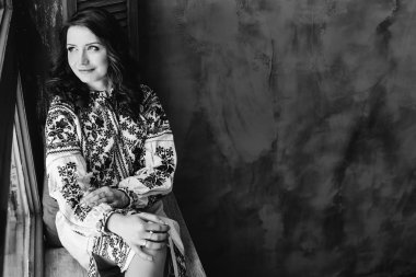 windo üzerinde oturan bir şık işlemeli elbiseli güzel kadın