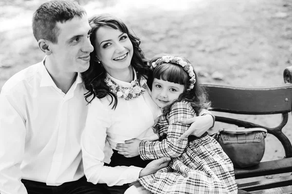 Família feliz sentado em um banco em fotografia em preto e branco . — Fotografia de Stock