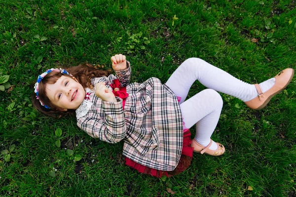 Una niña con un vestido y una corona en la cabeza se encuentra en el prado un — Foto de Stock