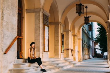 bir taş merdiven ve onun kemer üstü fener ile oturan uzun ve güzel saçlı bir kız
