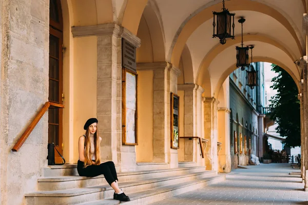 bir taş merdiven ve onun kemer üstü fener ile oturan uzun ve güzel saçlı bir kız