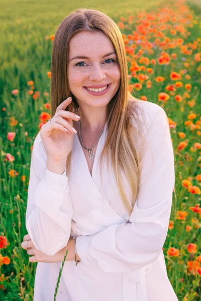 Primer plano de chica con pecas sobre un fondo de amapolas rojas un — Foto de Stock