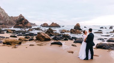 Kayalık deniz kıyıları ve yüksek uçurumlar. Kasvetli bir gün. Damat buna hayran.