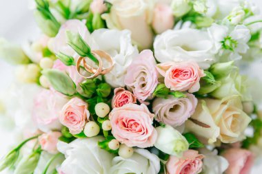 Düğün buketi ve altın alyanslara yakın çekim.