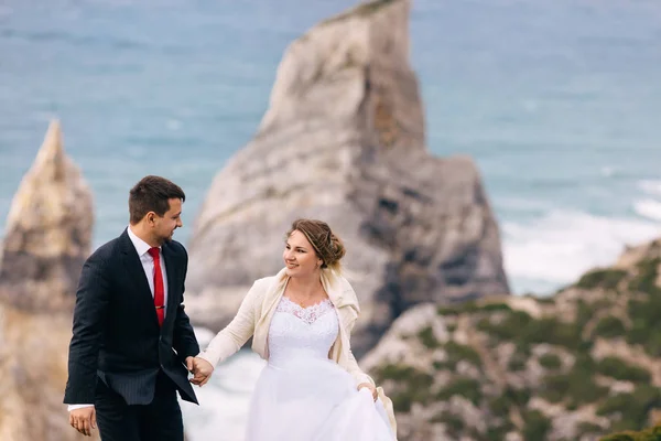 Güzel elbiseli gelin ve takım elbiseli damat el ele tutuşuyor. — Stok fotoğraf