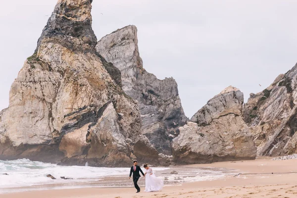 Deniz kıyısındaki kum ve kayalıklar. Yeni evliler eğleniyor. — Stok fotoğraf