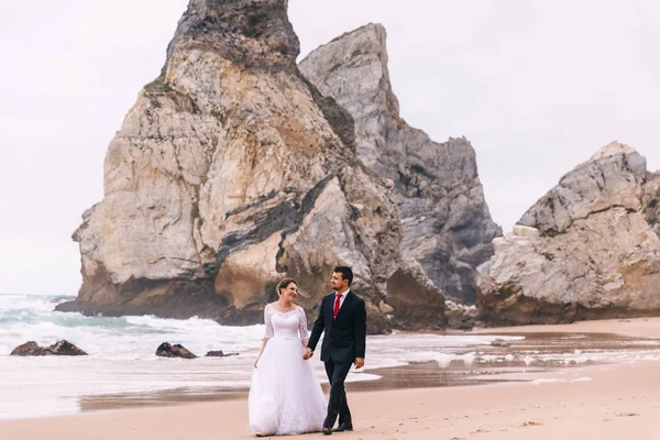Yeni evliler el ele tutuşup kumsalda yürüyorlar. — Stok fotoğraf