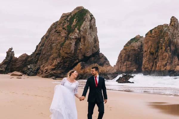 Yeni evliler el ele tutuşup okyanusun kumlu sahillerinde eğleniyorlar. — Stok fotoğraf