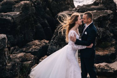 Yeni evliler büyük taşların arkasında sarılıp gülümsüyor. profi