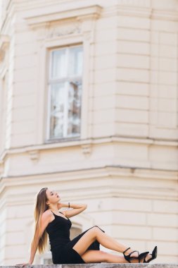 Binanın arka planında siyah elbiseli güzel poz veren kız. profi