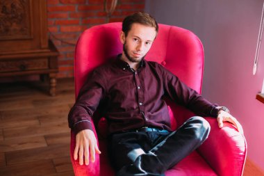 Resmi düğmeli elbiseli bir adam büyük bir kolçakta saygılı bir şekilde oturur.