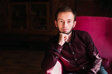 Koltuktaki ciddi sakallı adama yakın çekim. Kameraya bak..