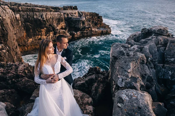 Yeni evliler birbirlerine sarılıp uzaktan bakıyorlar. kayalıklar — Stok fotoğraf