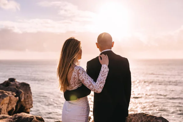 Braut und Bräutigam umarmen sich. Rückseite des Brautpaares bewundern die Sonne — Stockfoto