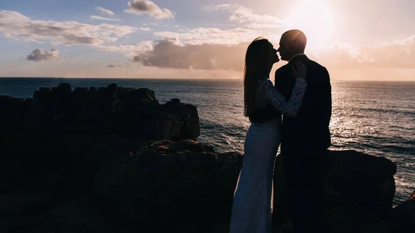 Novomanželé objímání a líbání na skalnatém břehu oceánu — Stock fotografie