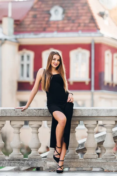 Magnifique fille dans une robe noire pose près des mains courantes et regarder — Photo