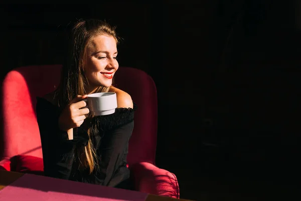 Красива дівчина з довгим волоссям п'є чай і сидить у кафе. молодий — стокове фото
