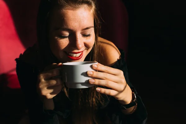 Young woman sitting in armchair and drinking tea in cafe. — 스톡 사진