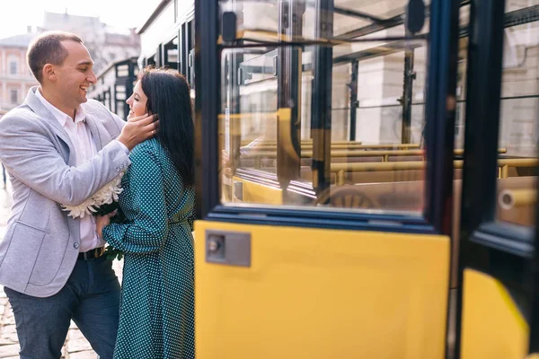 Chica sosteniendo un ramo de flores y un chico la abraza cerca de la —  Fotos de Stock