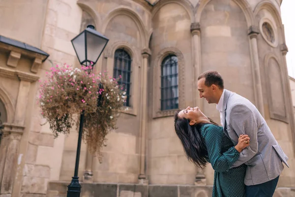 El tipo abraza a la chica y ella dobla la espalda. edificio con arche —  Fotos de Stock