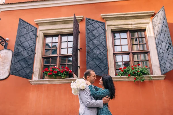 Couple amoureux sur fond de bâtiment orange. fille tenant un bou — Photo