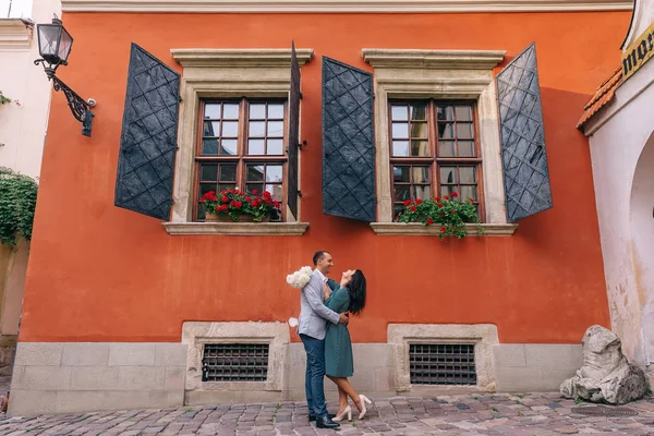 Mädchen mit einem Blumenstrauß und der Kerl umarmt sie. orange b — Stockfoto