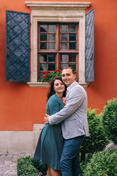 Verliebte Paare lächeln und blicken in die Kamera. orangefarbenes Gebäude — Stockfoto