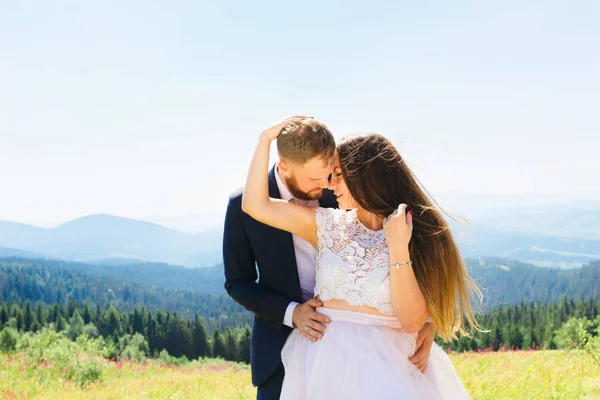 O noivo abraça a noiva por trás da cintura do lado de t — Fotografia de Stock