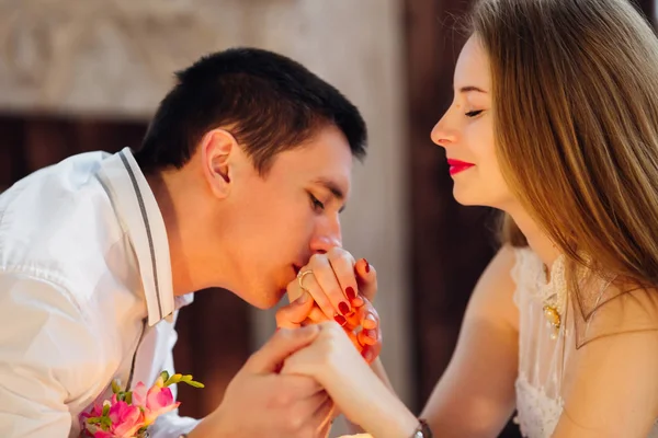 Il ragazzo bacia la mano della ragazza e si siedono al tavolo. oro r — Foto Stock