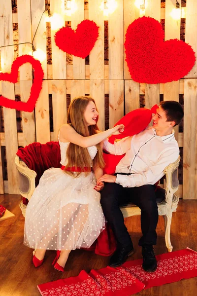 Kissenschlacht eines netten Paares in der Nähe einer Fotowand zum Valentinstag — Stockfoto