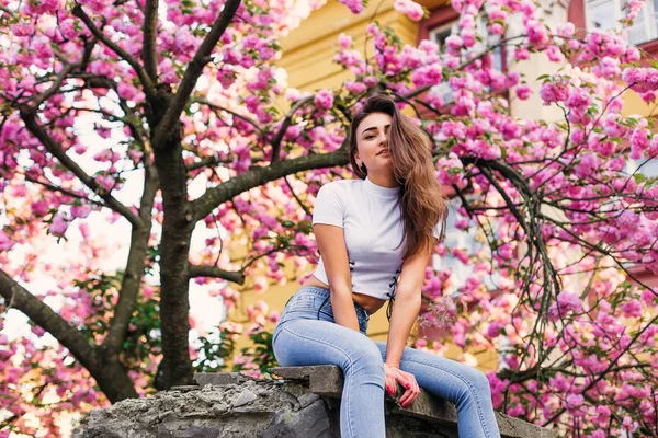 The girl seductively sits on the stone pillar of the fence and o — 스톡 사진