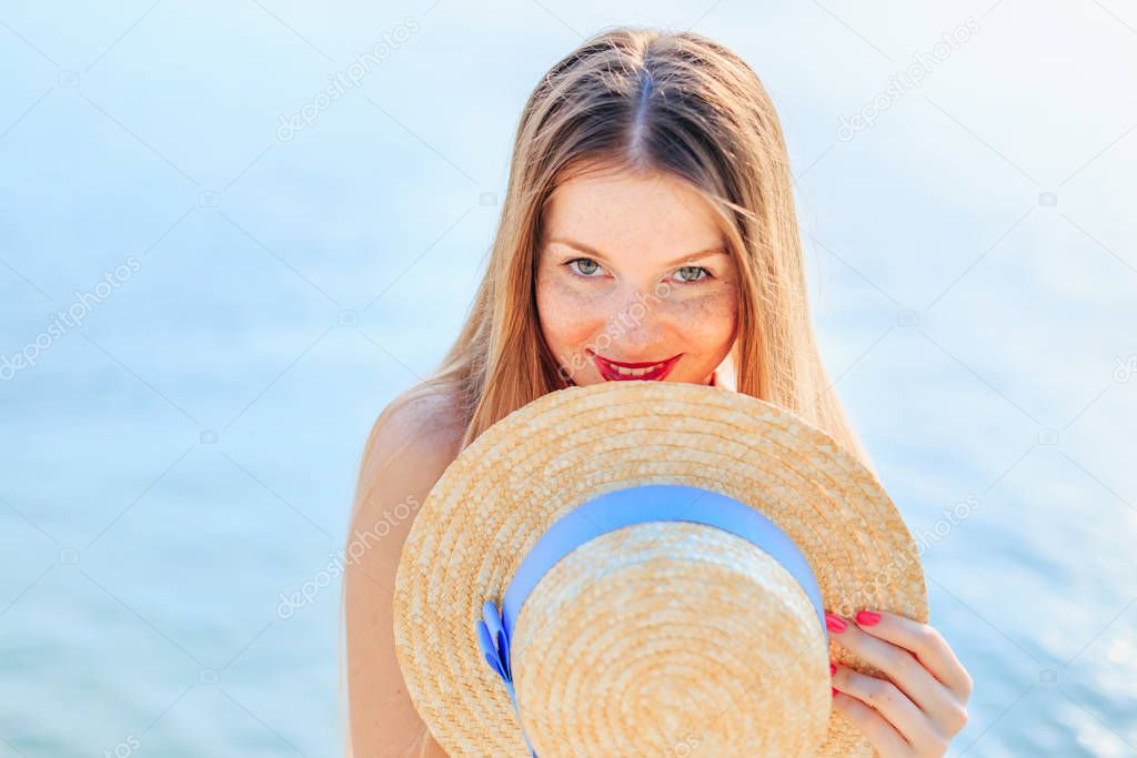 close up girl with freckles looking at camera and covered boater