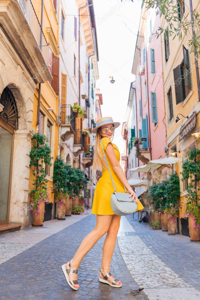 The girl in a yellow dress poses on the street of the city