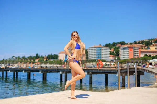Girl on a pier in a blue swimsuit on the background of city — 스톡 사진
