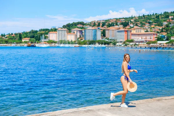 Genç bir kadın şehrin arka planında sahilde eğleniyor. kız — Stok fotoğraf