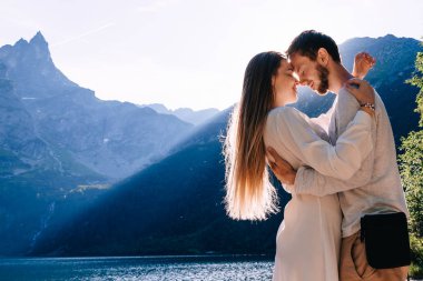 Erkek ve kız gözlerini kapatıp Ro 'nun arka planında sarılıyorlar.