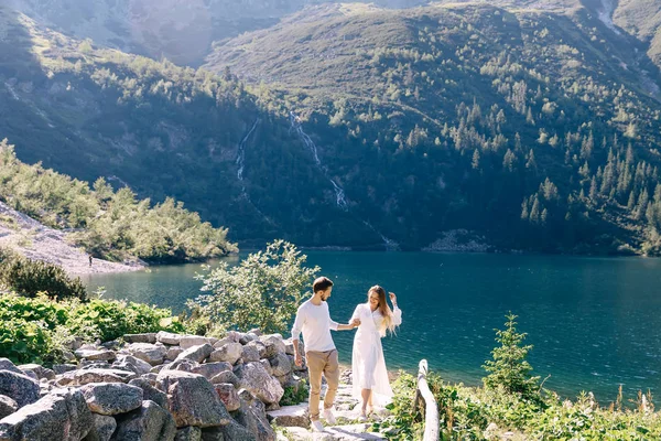 Pareja enamorada caminando por un camino de piedra. montañas cubiertas de ingenio — Foto de Stock