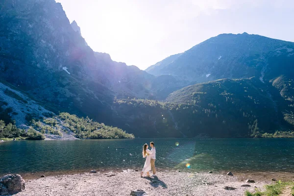 Paar, das sich am Ufer eines schönen Sees umarmt. Sonnenlicht illumi — Stockfoto
