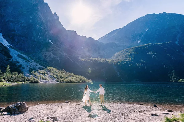 Mann und Mädchen halten sich an den Händen und schauen sich am Ufer an — Stockfoto