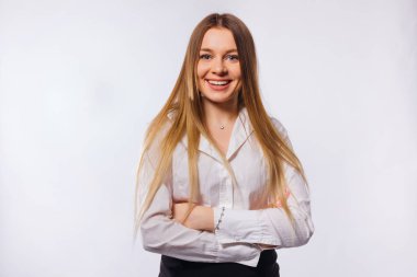 Kız gülümser ve kollarını kavuşturur. Resmi beyaz giyen kadın.