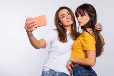 girls smiling and taking selfies on mobile phone. studio. stylis