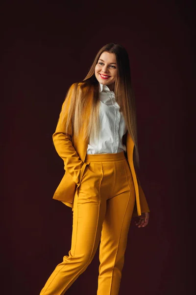 Piękna dziewczyna w żółtym garniturze uśmiecha się. casual ubrania dla busin — Zdjęcie stockowe