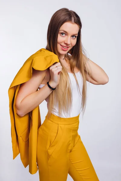 Girl with a long hair holds a yellow jacket on her shoulder. yel — Stock Photo, Image