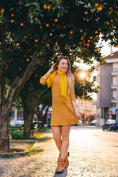 Ragazza con i capelli lunghi in un vestito. Cammina. strada con aranci . — Foto Stock