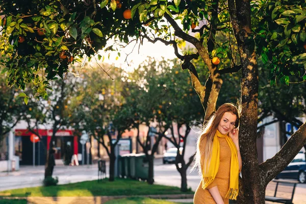 Menina bonita olhar para a câmera e sorrisos. inclinar-se contra a árvore — Fotografia de Stock