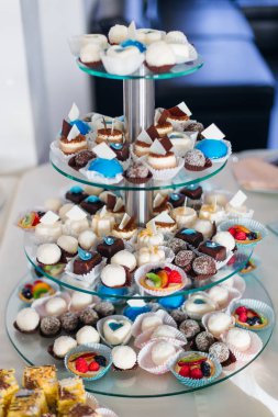 Çeşitli tatlılarla çok katlı stantlar. Düğün resepsiyonunda çikolata