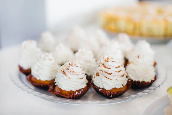 Magdalenas cubiertas con crema blanca en un plato. banquete de boda . — Foto de Stock