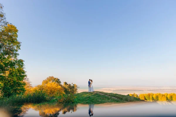 Pasgetrouwden op de herfstweide op de achtergrond van blauwe wolkenloze s — Stockfoto